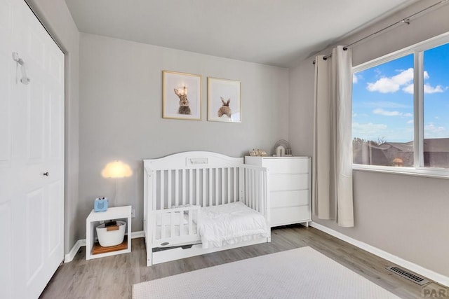 bedroom featuring a closet, visible vents, baseboards, and wood finished floors