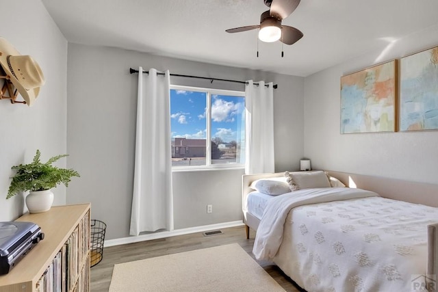 bedroom with ceiling fan, light wood-type flooring, visible vents, and baseboards