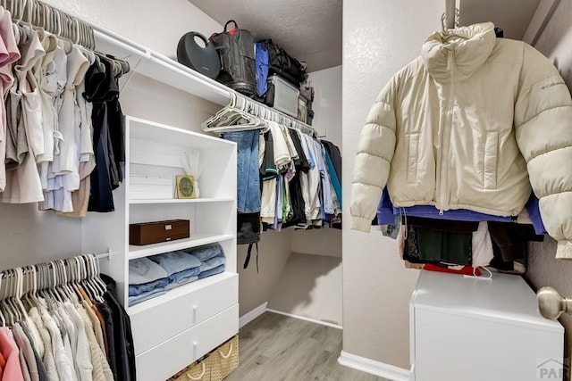 walk in closet with wood finished floors