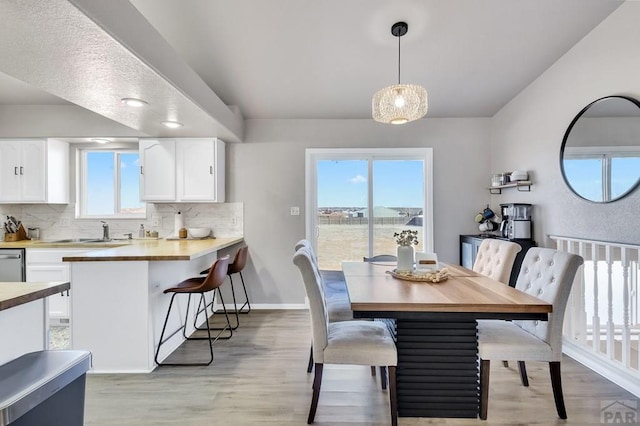 dining area with light wood-style floors, plenty of natural light, and baseboards