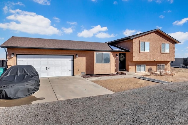 tri-level home featuring concrete driveway, roof with shingles, an attached garage, and stucco siding