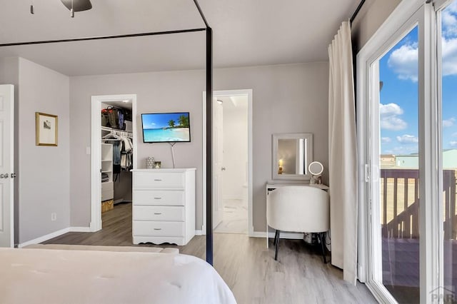 bedroom featuring access to outside, connected bathroom, a walk in closet, and wood finished floors