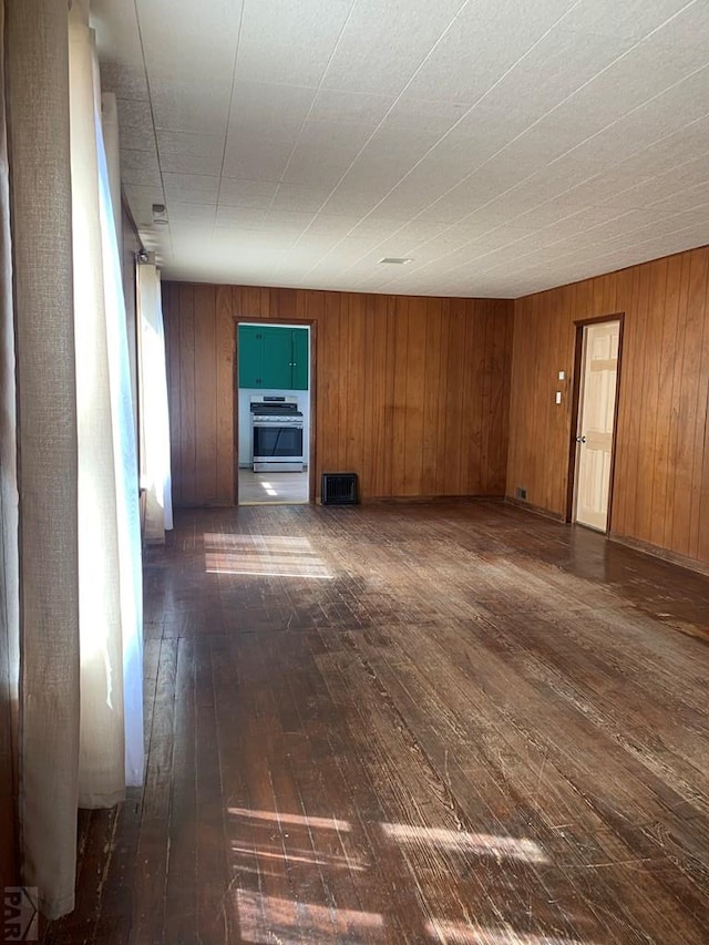 309 Walsen Ave, Walsenburg, CO 81089 - unfurnished room with dark wood-style flooring, visible vents, and wood walls