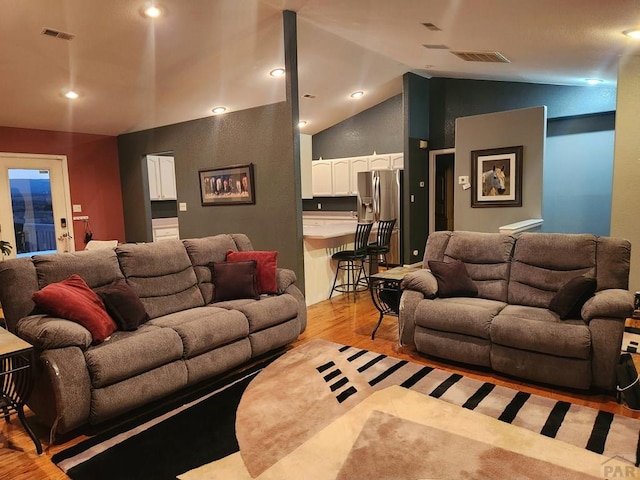 living room featuring lofted ceiling, light wood-style flooring, visible vents, and recessed lighting