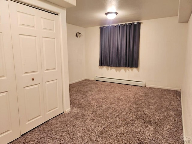 spare room featuring carpet floors, baseboards, and a baseboard heating unit