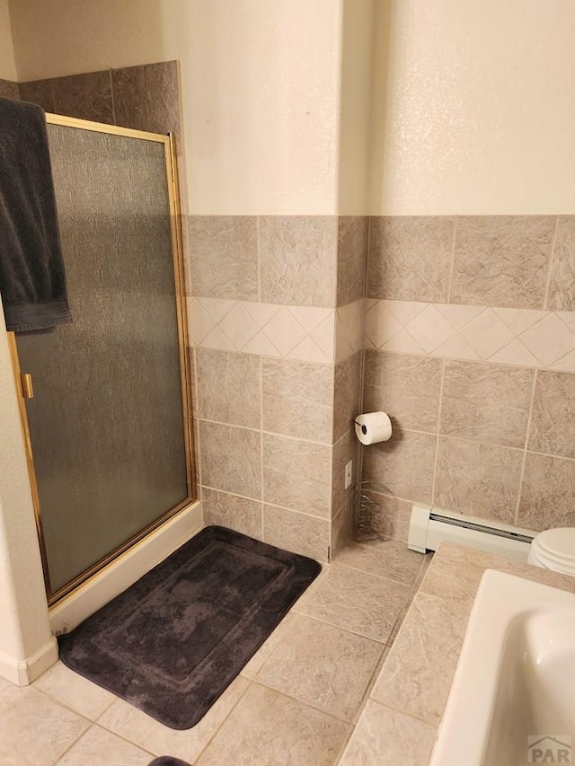 bathroom with a baseboard radiator, a shower stall, and tile walls