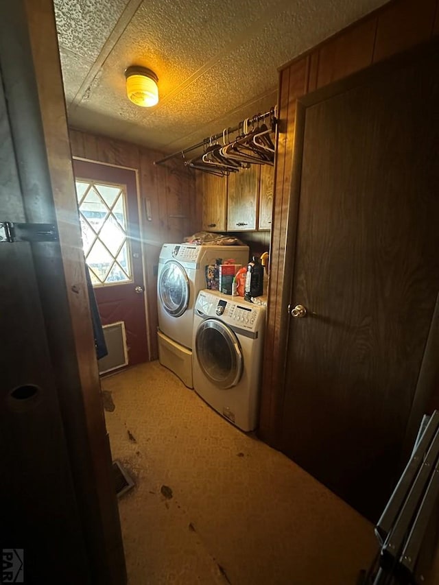 laundry area with a textured ceiling, cabinet space, and washing machine and dryer