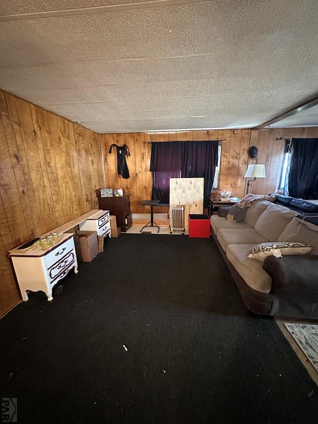 carpeted living room with a textured ceiling and wood walls