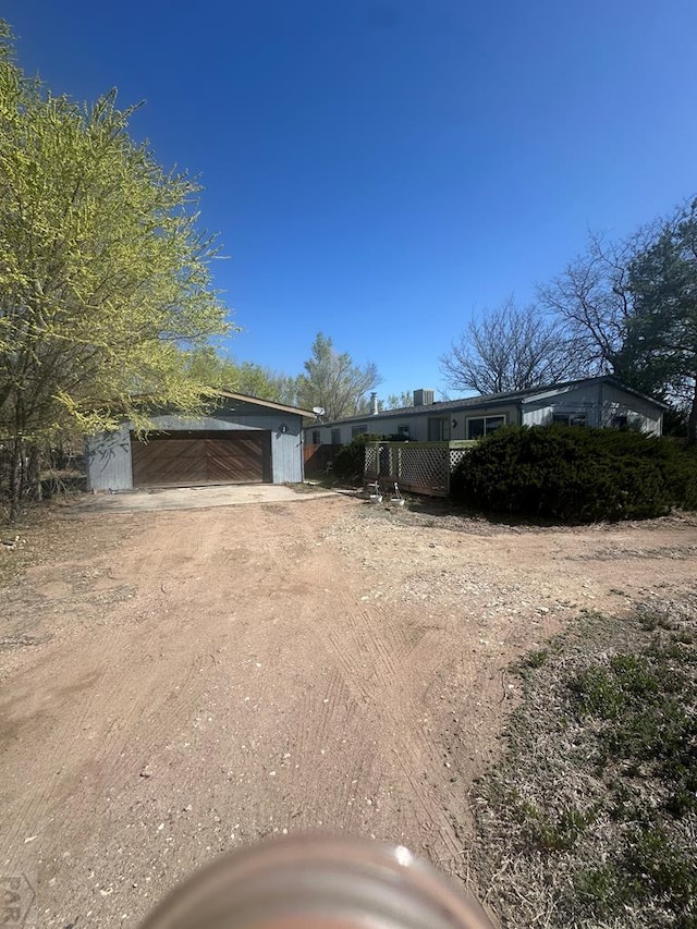 exterior space with a garage, an outdoor structure, and dirt driveway
