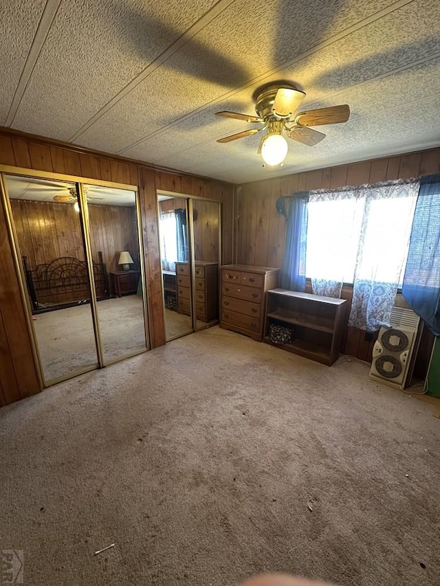 bedroom with wood walls, multiple windows, multiple closets, and ceiling fan