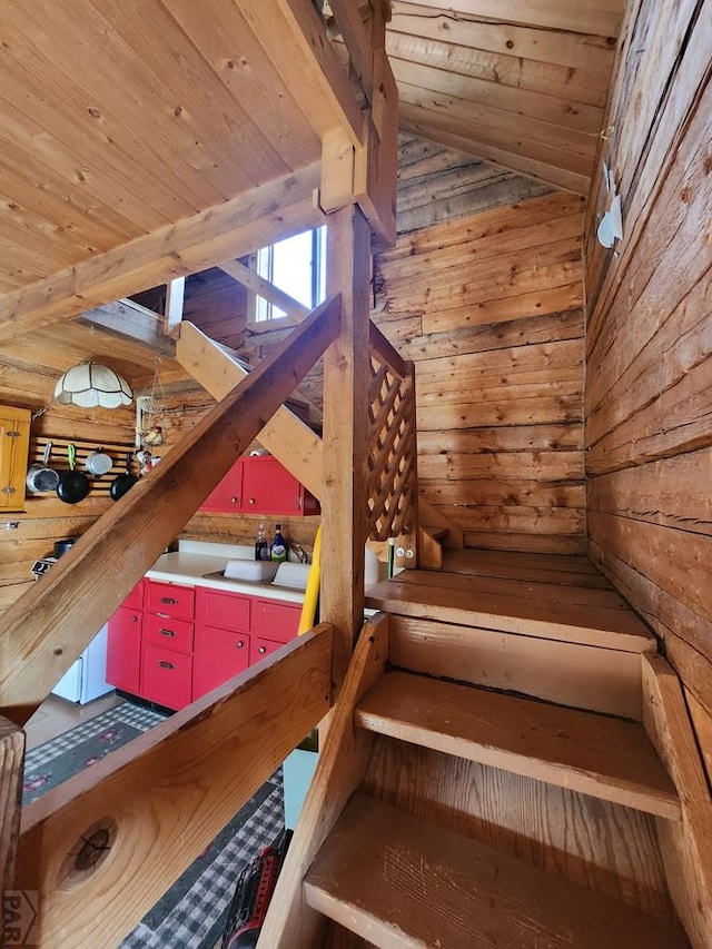 stairway with wood ceiling, vaulted ceiling, and wooden walls