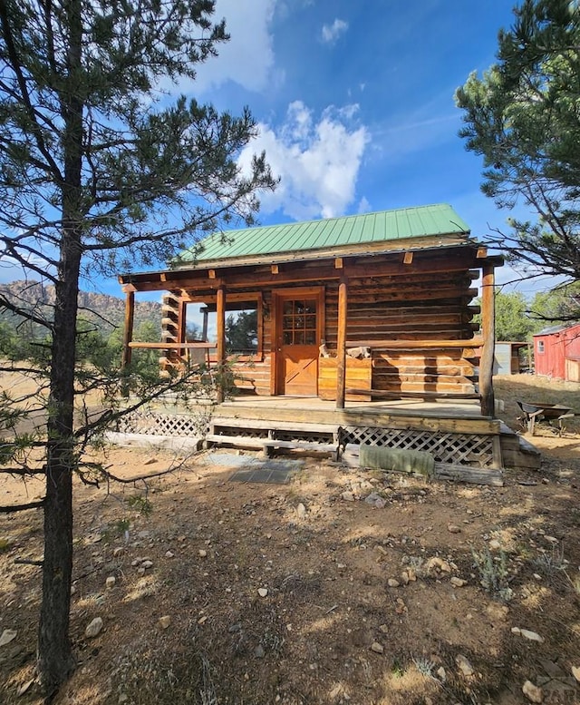 view of front of property with a porch, log siding, and metal roof