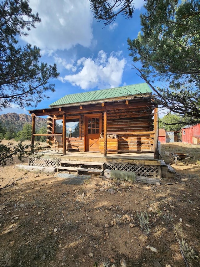 exterior space featuring metal roof, an outdoor structure, and log siding