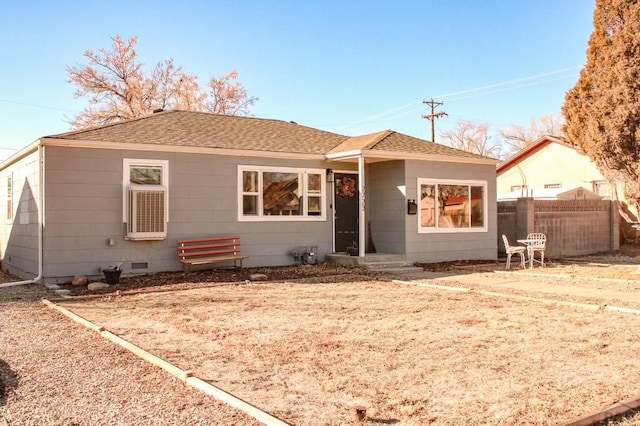 back of property with a shingled roof, crawl space, and fence