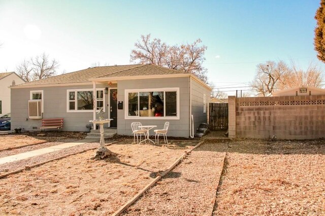 rear view of property with entry steps, roof with shingles, and fence