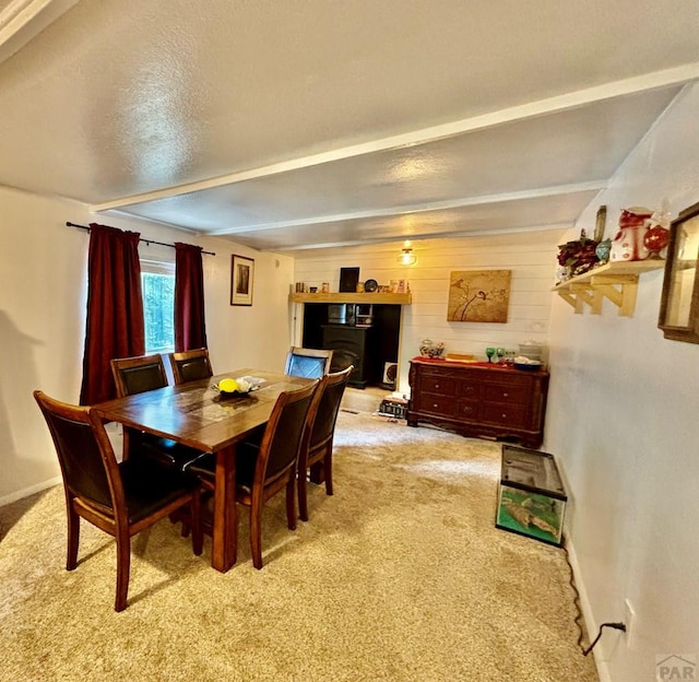 dining area featuring light carpet, baseboards, and beam ceiling