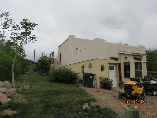 exterior space featuring stucco siding and a yard