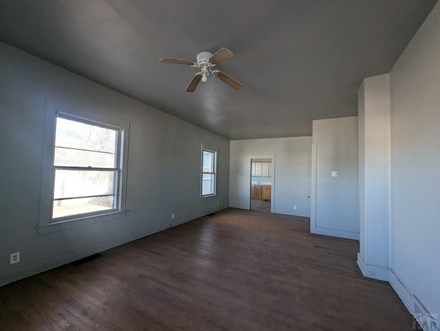 unfurnished room featuring ceiling fan, dark wood-style flooring, and baseboards