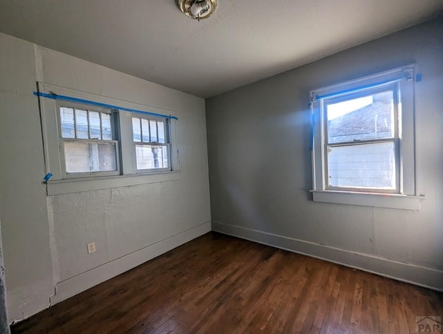 empty room with plenty of natural light, dark wood finished floors, and baseboards