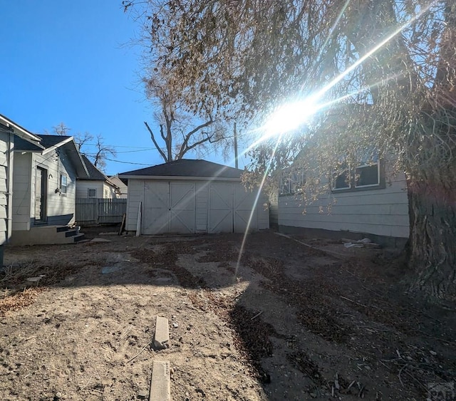 back of property featuring a storage shed, fence, and an outbuilding