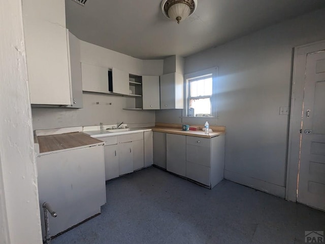 kitchen featuring refrigerator, white cabinets, light countertops, and open shelves