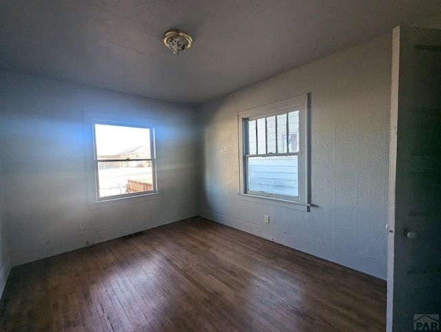 unfurnished room featuring visible vents and dark wood-style flooring