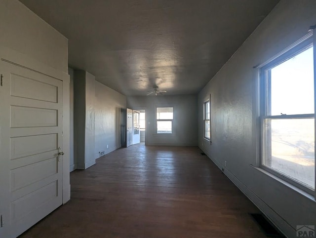 unfurnished room featuring dark wood-style flooring, a ceiling fan, and baseboards