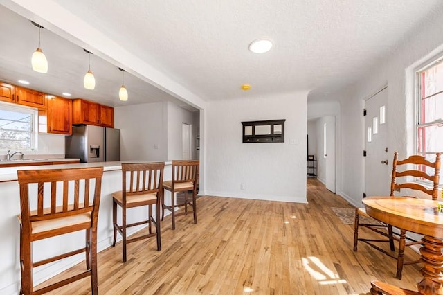 501 E Main St, Trinidad, CO 81082 - kitchen featuring stainless steel fridge with ice dispenser, brown cabinets, light countertops, a textured ceiling, and light wood finished floors