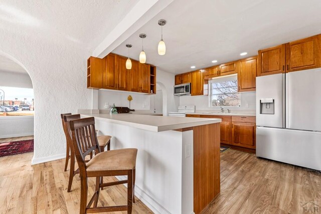 501 E Main St, Trinidad, CO 81082 - kitchen with refrigerator with ice dispenser, stainless steel microwave, open shelves, stove, and light wood finished floors