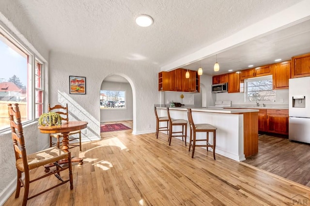 501 E Main St, Trinidad, CO 81082 - kitchen with white appliances, a textured ceiling, a textured wall, brown cabinetry, and arched walkways