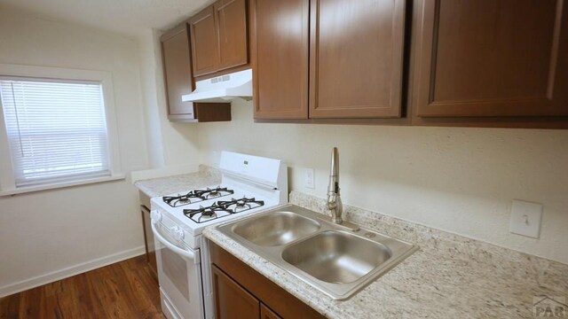 1434 E Evans Ave, Pueblo, CO 81004 - kitchen featuring under cabinet range hood, light countertops, white range with gas cooktop, a sink, and dark wood-style floors
