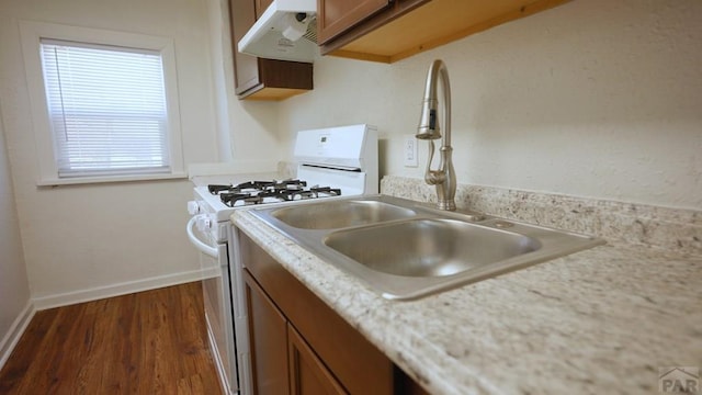 1434 E Evans Ave, Pueblo, CO 81004 - kitchen featuring light countertops, white range with gas cooktop, brown cabinetry, and under cabinet range hood