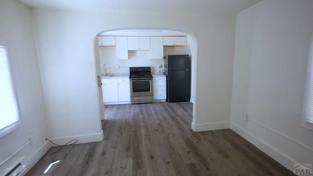 1434 E Evans Ave, Pueblo, CO 81004 - kitchen with electric range, arched walkways, white cabinets, freestanding refrigerator, and wood finished floors