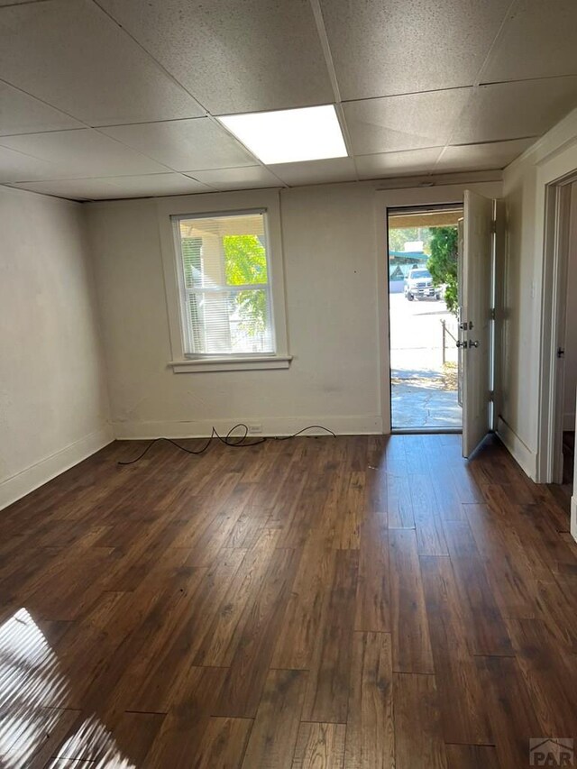 1434 E Evans Ave, Pueblo, CO 81004 - unfurnished room with dark wood-style flooring, a paneled ceiling, and baseboards