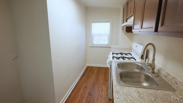 1434 E Evans Ave, Pueblo, CO 81004 - kitchen featuring a sink, light countertops, baseboards, dark wood-type flooring, and white gas stove