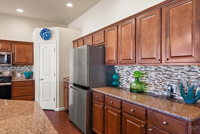 kitchen featuring light stone countertops, appliances with stainless steel finishes, brown cabinets, tasteful backsplash, and dark wood finished floors