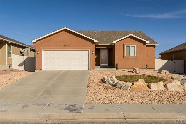 single story home with a garage, concrete driveway, fence, and stucco siding