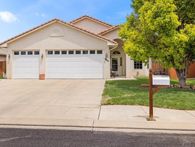 view of front of home featuring stucco siding, an attached garage, driveway, a tiled roof, and a front lawn