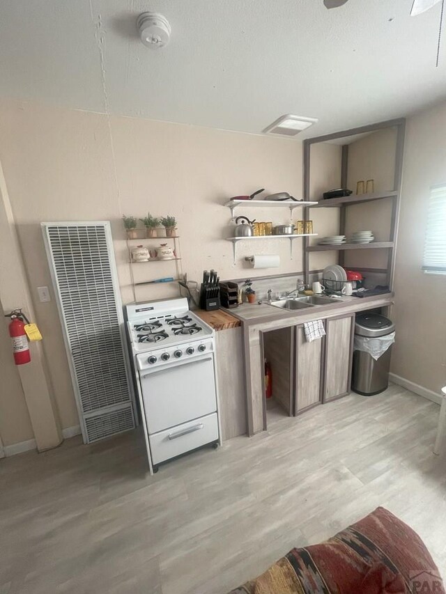 106 E 4th St, Antonito, CO 81120 - kitchen with a heating unit, white range with gas cooktop, open shelves, and light wood-type flooring