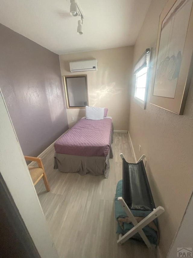 106 E 4th St, Antonito, CO 81120 - bedroom featuring a wall mounted air conditioner, wood finished floors, rail lighting, and baseboards