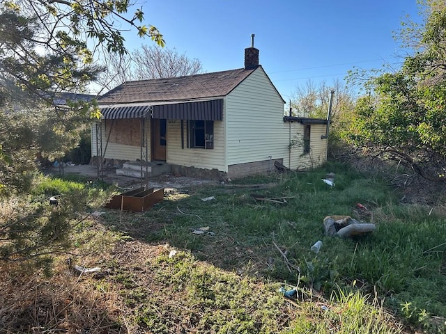 exterior space featuring roof with shingles, a chimney, and entry steps