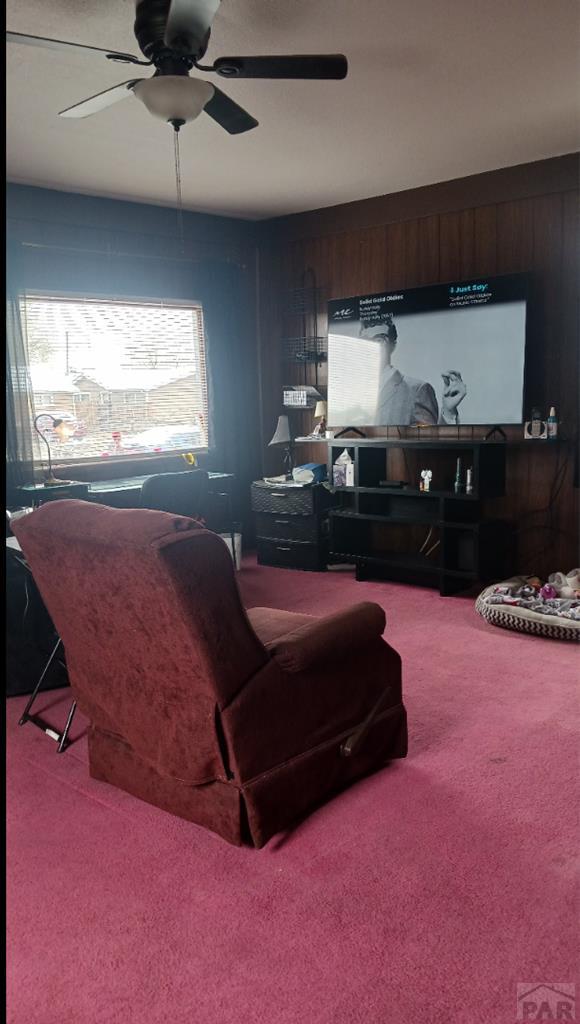 2318 W 17th St, Pueblo, CO 81003 - living room with carpet, a ceiling fan, and wood walls