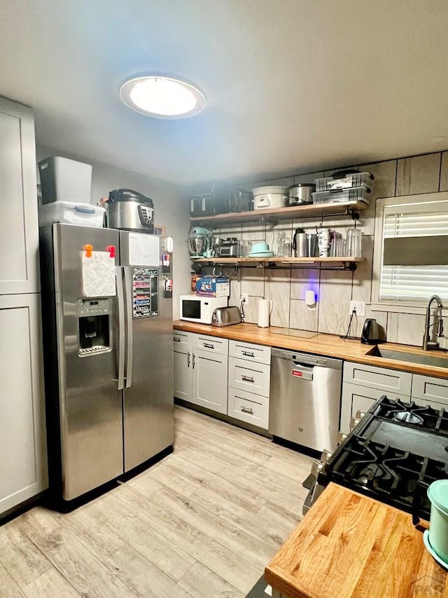 1127 W 12th St, Pueblo, CO 81003 - kitchen featuring appliances with stainless steel finishes, wood counters, a sink, and light wood-style flooring
