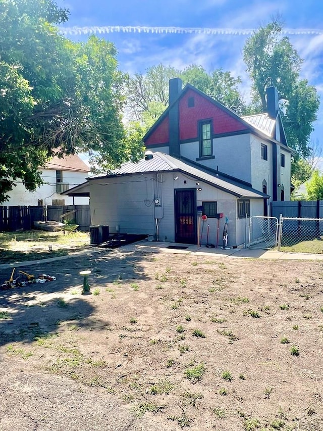 1127 W 12th St, Pueblo, CO 81003 - back of house featuring a chimney, metal roof, a gate, a standing seam roof, and central air condition unit
