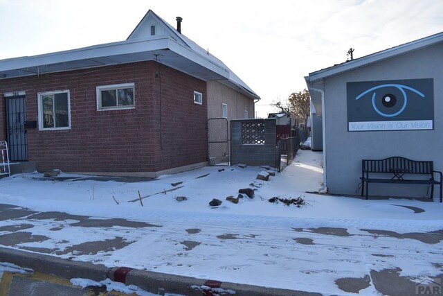 view of snowy exterior featuring brick siding