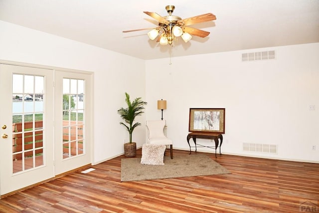 living area with ceiling fan, light wood-type flooring, and visible vents