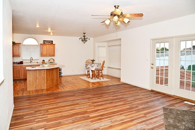 kitchen featuring light countertops, brown cabinetry, a kitchen island, a sink, and light wood-type flooring