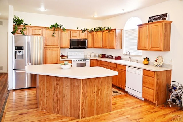 kitchen featuring appliances with stainless steel finishes, light countertops, a kitchen island, and a sink