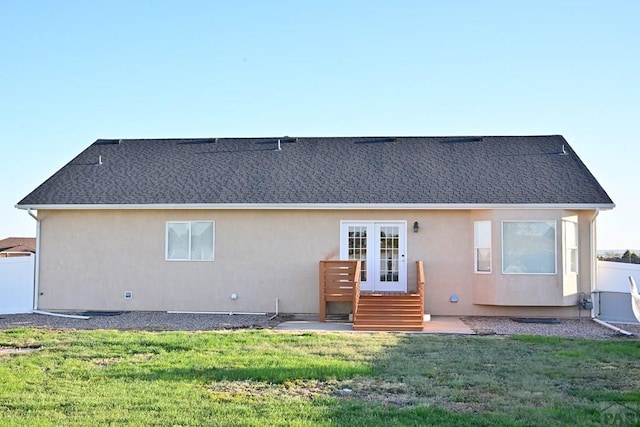 rear view of property with french doors, a yard, and stucco siding