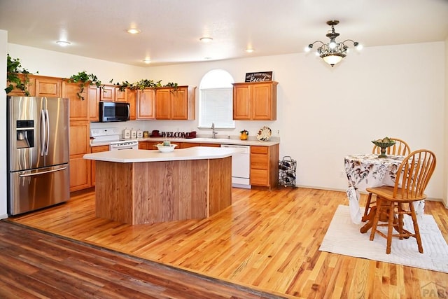 kitchen with stainless steel appliances, a kitchen island, light wood-style floors, light countertops, and brown cabinetry